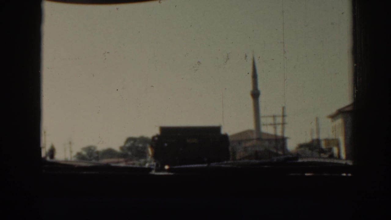 Car-window view of a dark truck on a city street with a mosque minaret behind it.