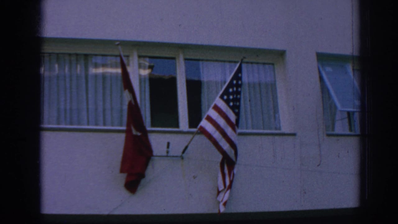 Turkish and American flags mounted below windows on a pale building facade.