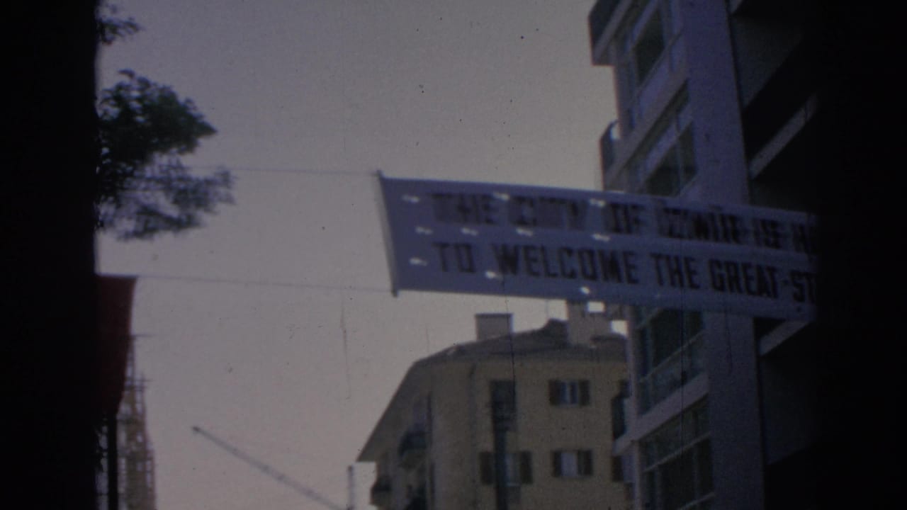 Street banner stretched between apartment buildings with text partly visible.
