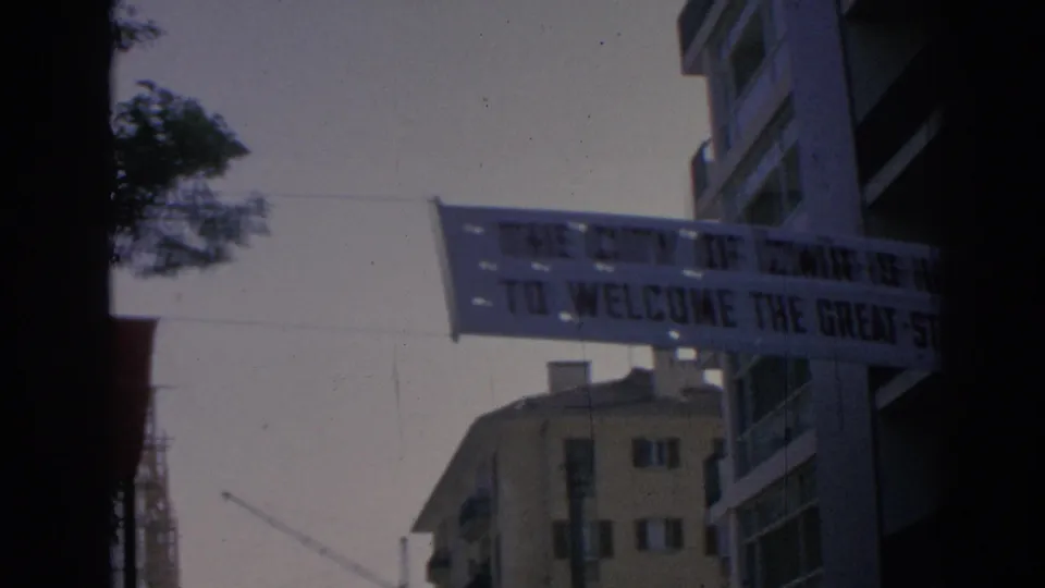 1962 Izmir street view with a welcome banner hanging across the road between apartment buildings.