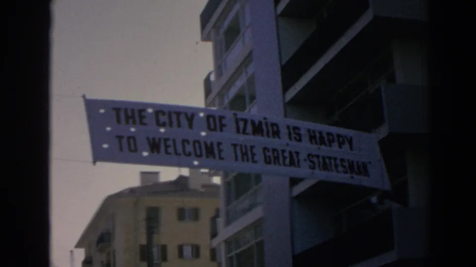 A suspended Izmir welcome banner is more legible as it hangs beside apartment balconies in the 1962 footage.