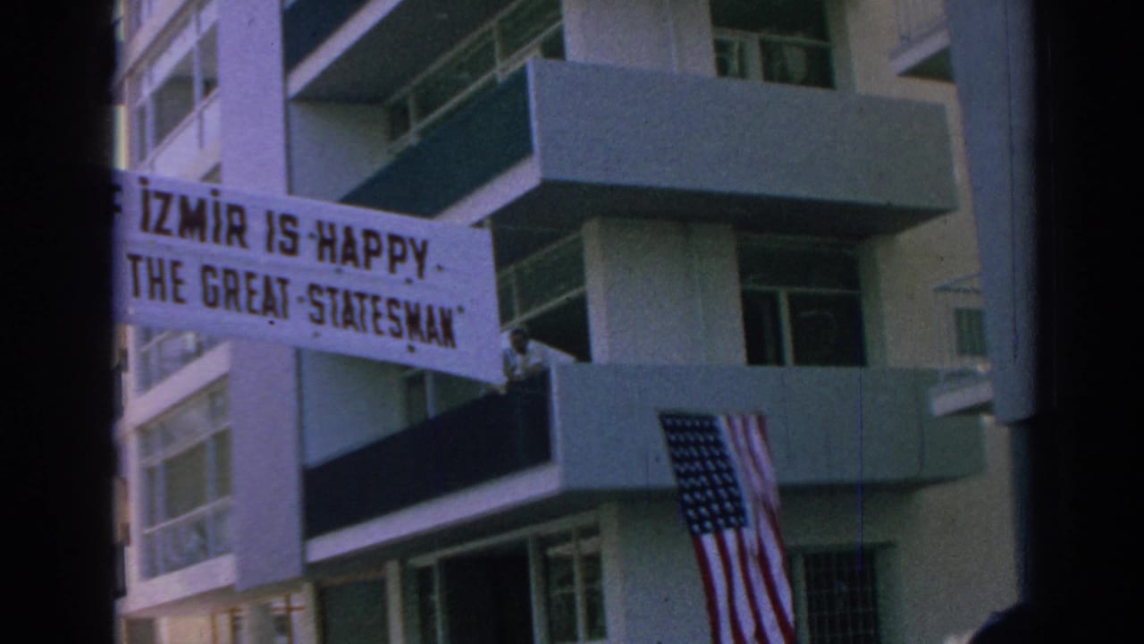 Banner on a modern building reads Izmir is happy, with an American flag below.