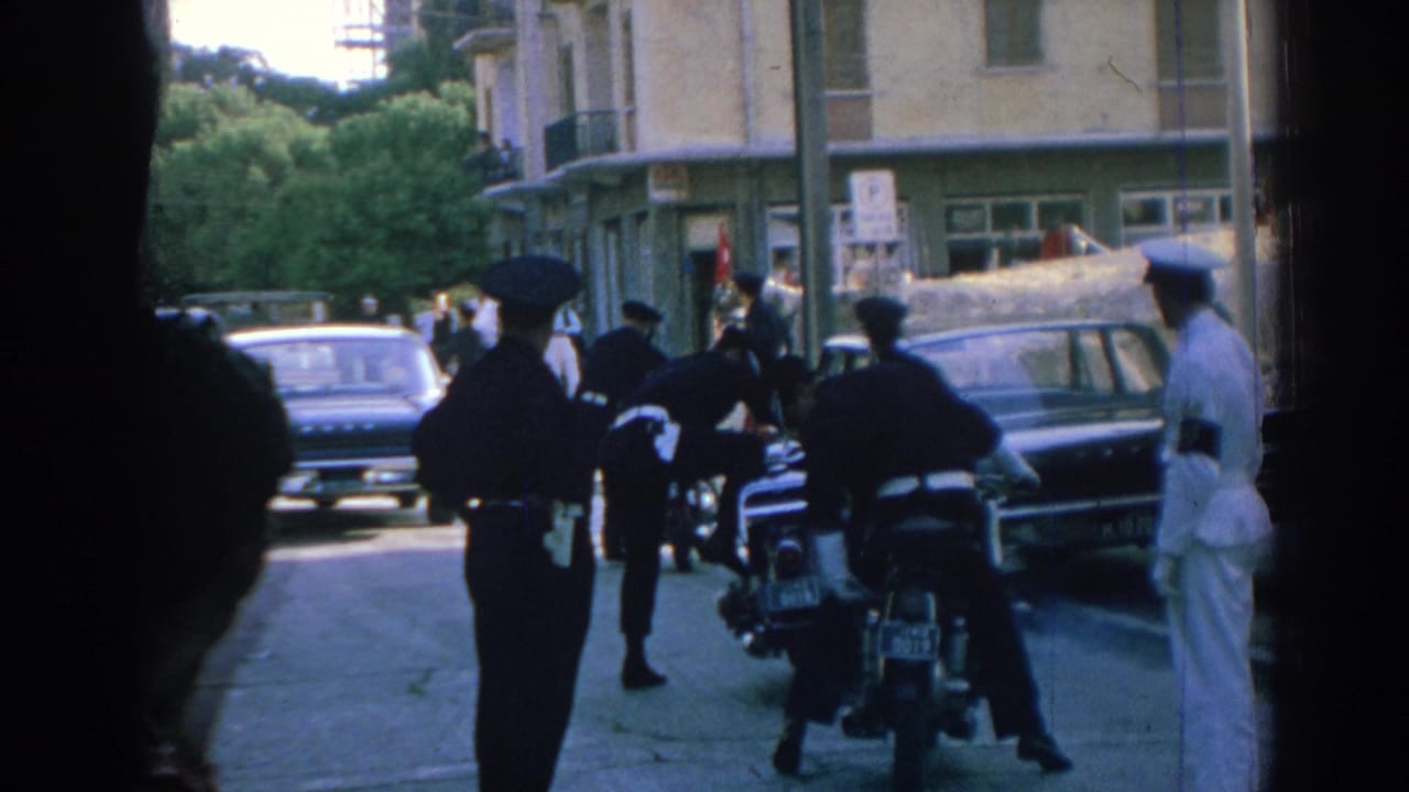 Police officers stand near motorcycles and parked cars on a city street.