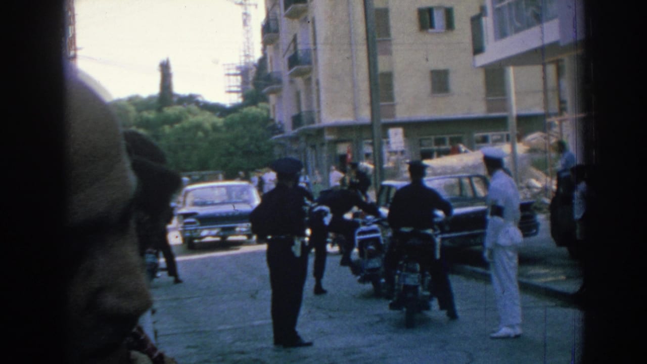 1962 Izmir street scene with police near motorcycles, a sailor in white, parked cars, and a close foreground pedestrian.