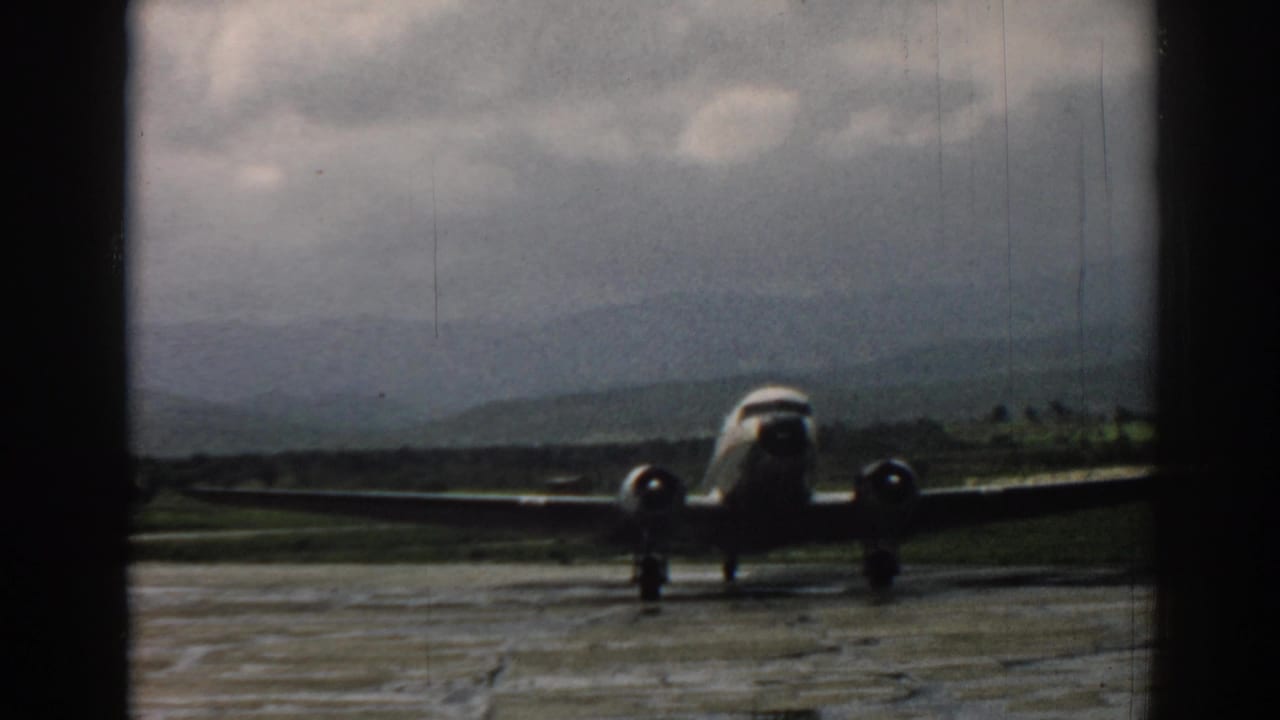 The aircraft appears closer on the Izmir aerodrome, with its wings spanning the frame against a cloudy 1960s home-movie backdrop.