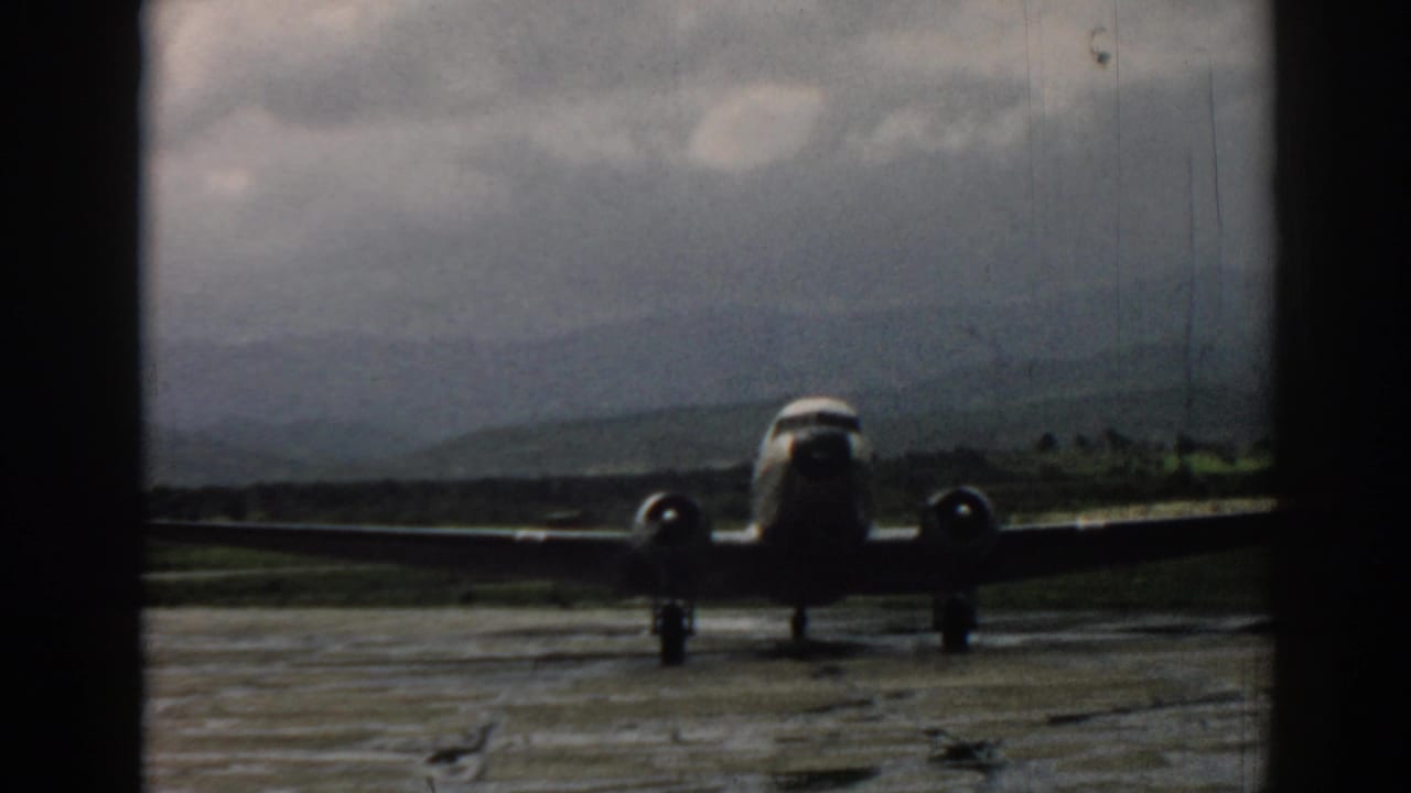 Head-on view of a twin-engine propeller airplane on the wet Izmir aerodrome, recorded in soft-grained 8mm color footage.