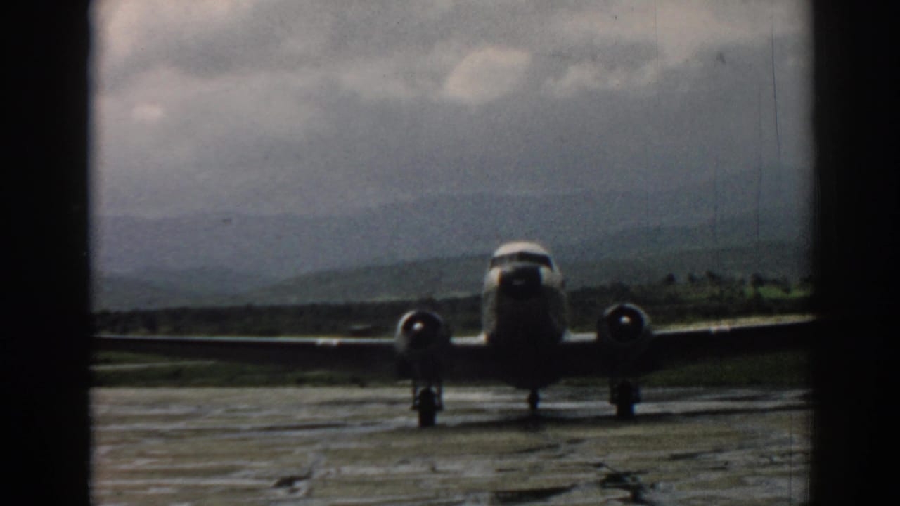 Late frame of the 1962 Izmir clip with the propeller aircraft closer on the tarmac, hills and gray clouds still visible behind it.