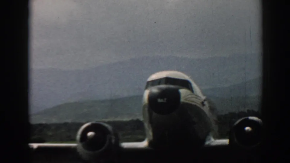 Closer 1962 Izmir view of the airliner's nose, engines, and wing, with the runway and hazy hills behind it.