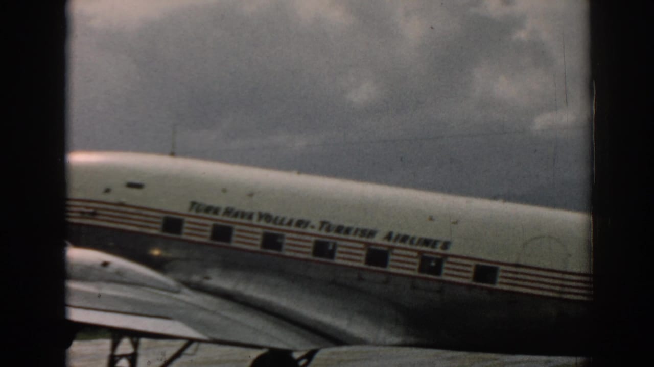 In the Izmir 1962 home-movie frame, the Turkish Airlines fuselage passes behind a dark vertical frame with windows and wing visible.