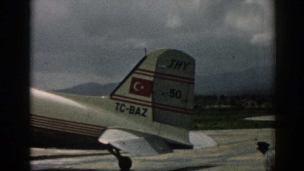 Turkish Airlines aircraft tail and rear fuselage at Izmir, with hills beyond the airport apron.