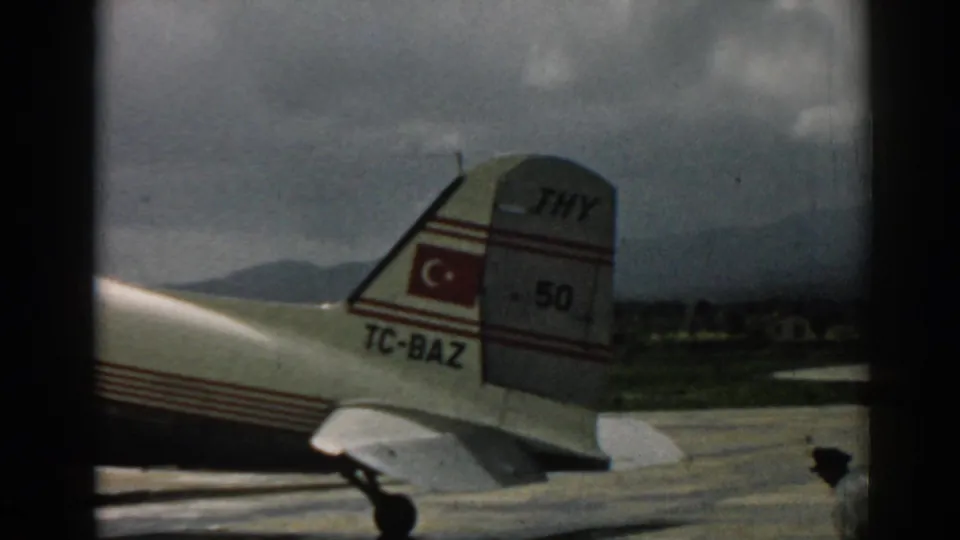 Turkish Airlines aircraft tail and rear fuselage at Izmir, with hills beyond the airport apron.