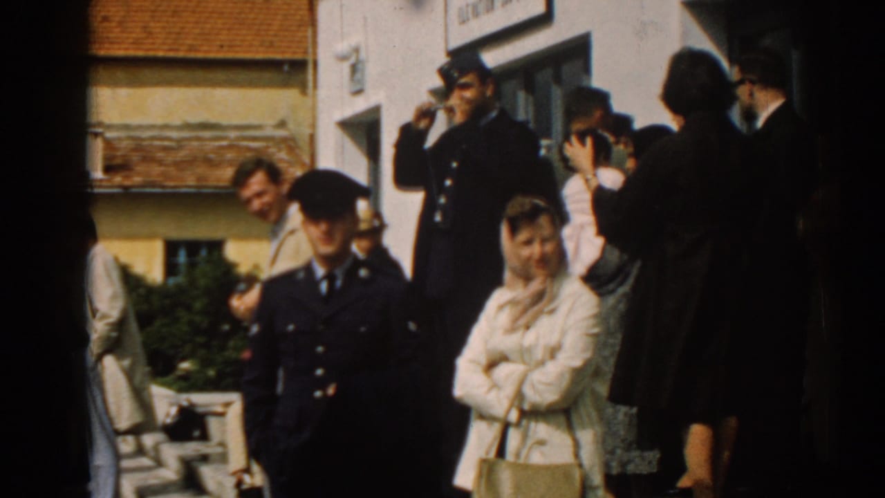 Terminal-side crowd in Izmir, Turkey, with uniformed men, civilians, and a woman in a light coat visible.