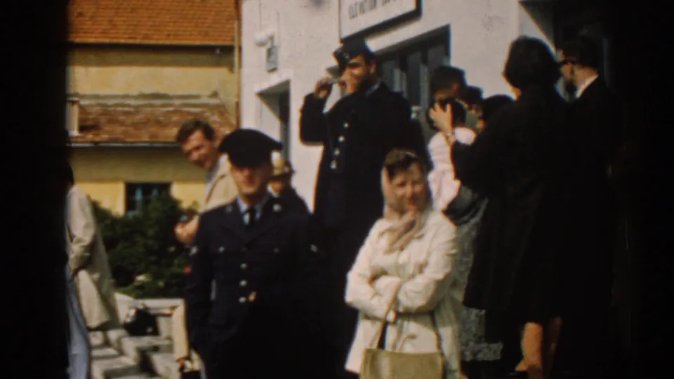 Terminal-side crowd in Izmir, Turkey, with uniformed men, civilians, and a woman in a light coat visible.