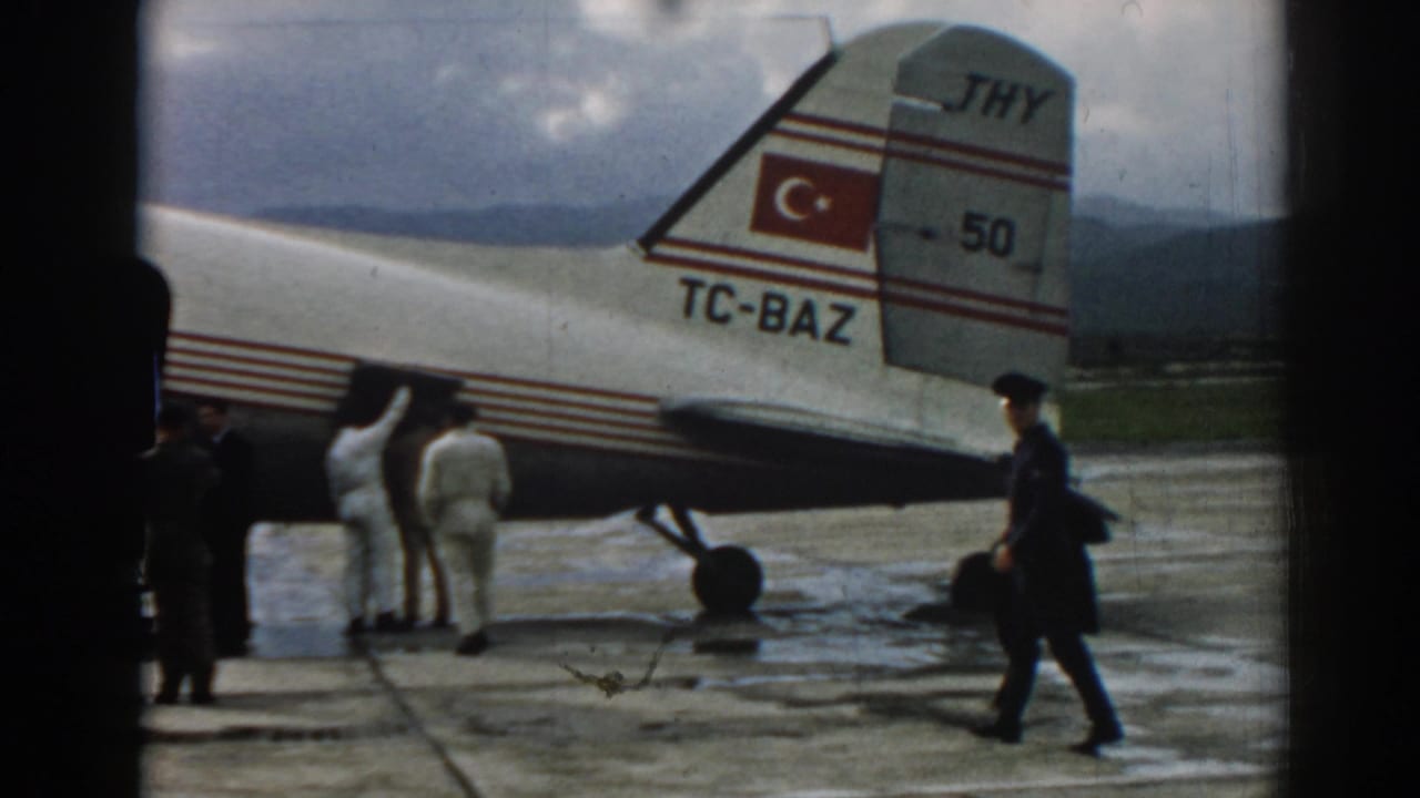 Men standing near the rear of a Turkish Airlines aircraft on a wet tarmac.