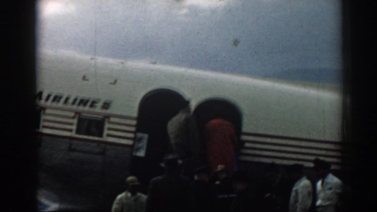Passengers gather near boarding stairs beside a Turkish Airlines aircraft fuselage.