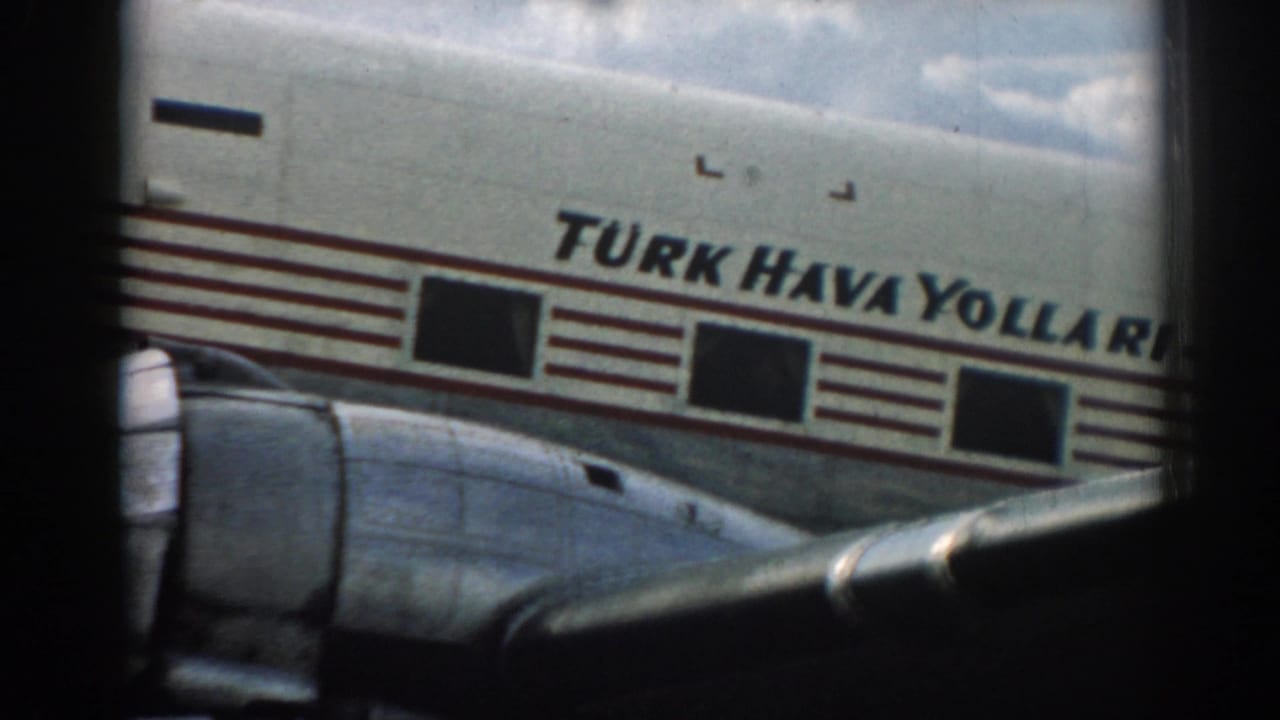 A soft 8mm frame shows the Turkish Airlines fuselage, red stripes, dark cabin windows, and wing section at Izmir Airport in 1962.