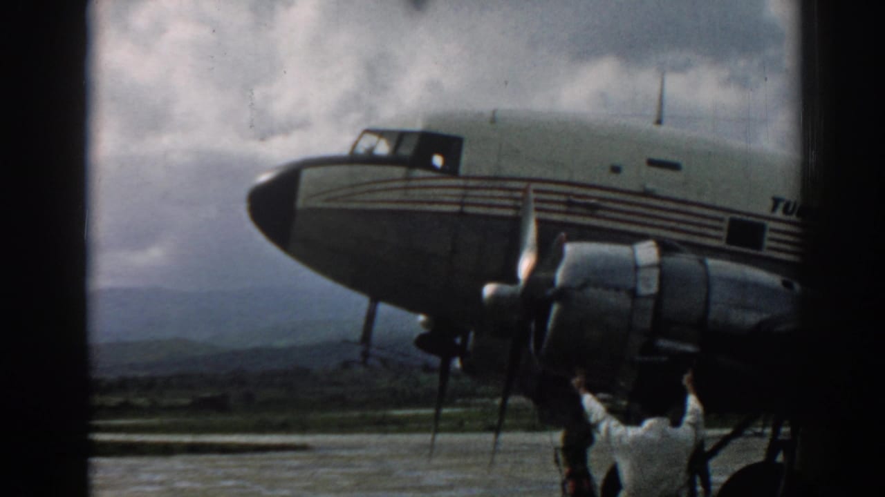 Close view of a striped propeller aircraft with a crew member standing below the engine.
