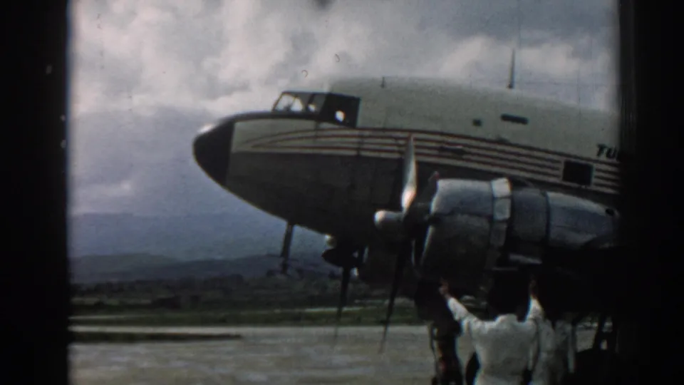 End frame from the 1962 Izmir clip showing the Turk Hava Yolları aircraft, radial engine, fuselage stripes, tarmac, and crew member.