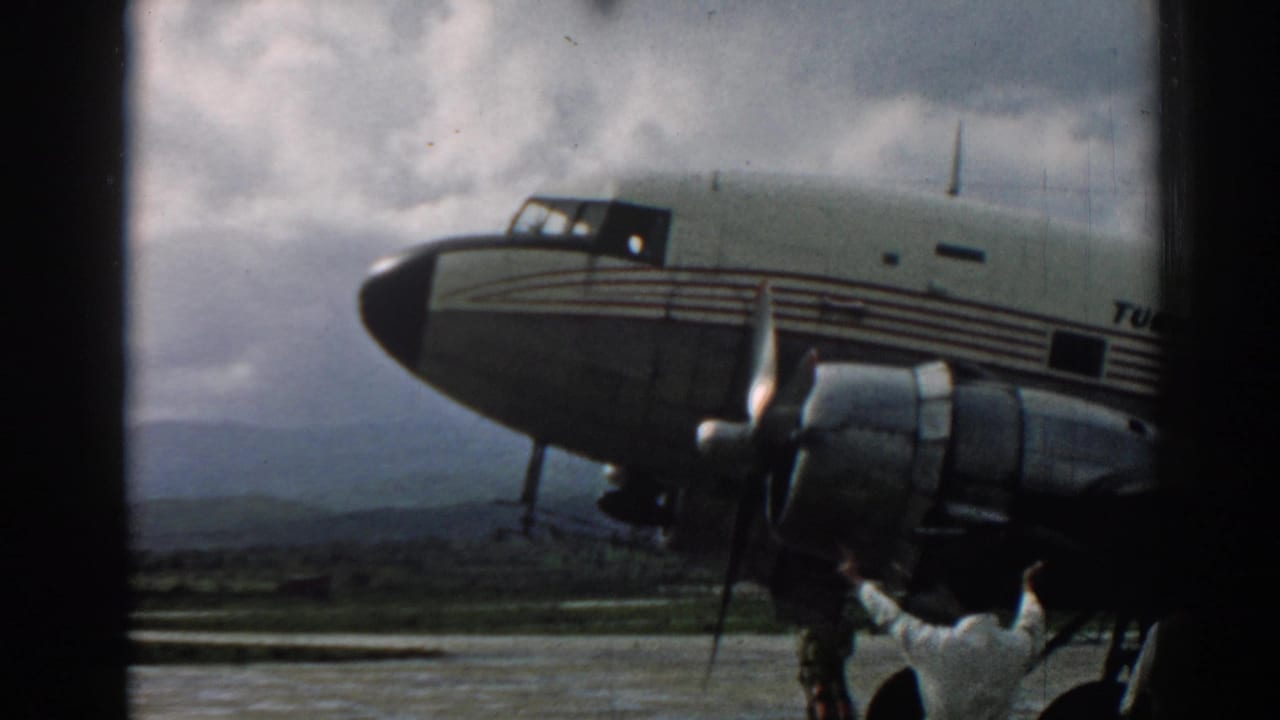 1962 Izmir runway view of a propeller aircraft with striped fuselage and crew working near the engine.