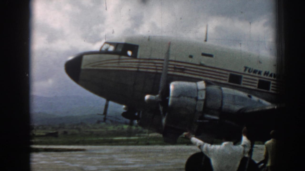 1962 Izmir airport frame showing the aircraft fuselage, propeller engine, and partial figures along the tarmac edge.