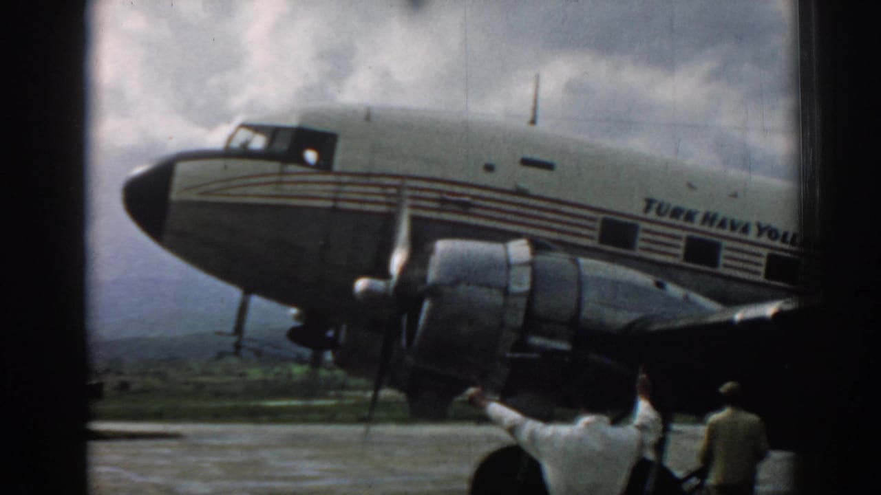 Turk Hava Yolları propeller airplane on a tarmac with two men in the foreground.