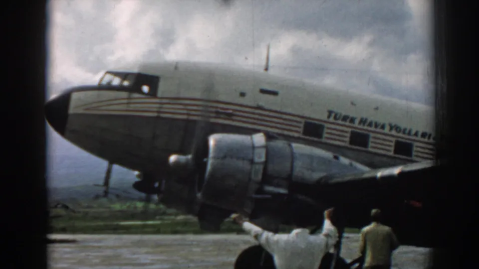 1962 Izmir tarmac view with the propeller engine prominent and a man raising his arms near the aircraft.