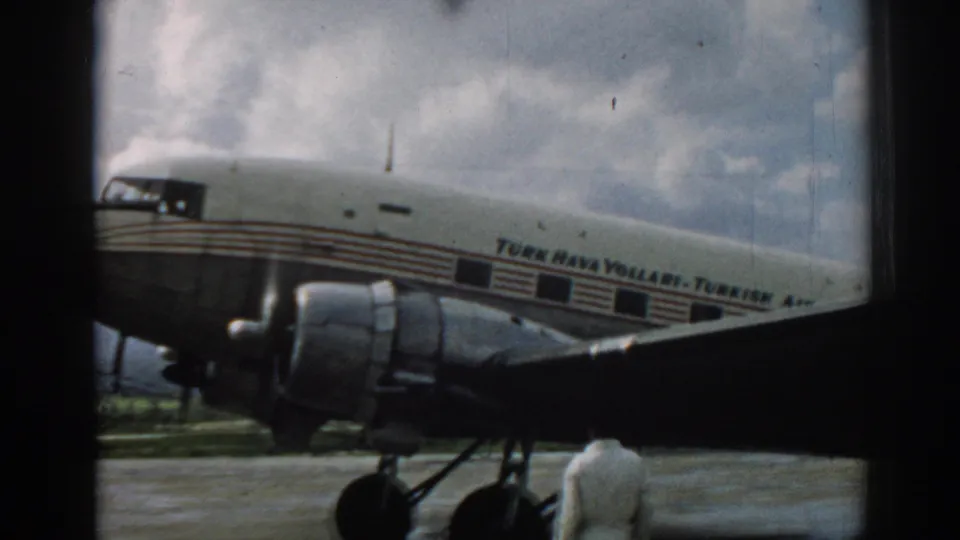 1962 Izmir home-movie frame showing the Turk Hava Yollari aircraft side and engine area through a window opening.