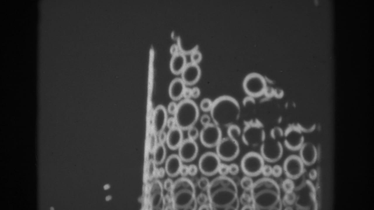 1962 Las Vegas home-movie frame showing a close view of circular animated lights on a tall sign at night.