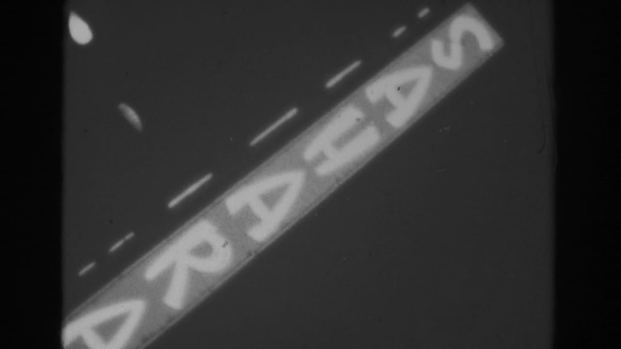 Diagonal illuminated Sahara sign against a dark sky with visible film grain and edge shadows.