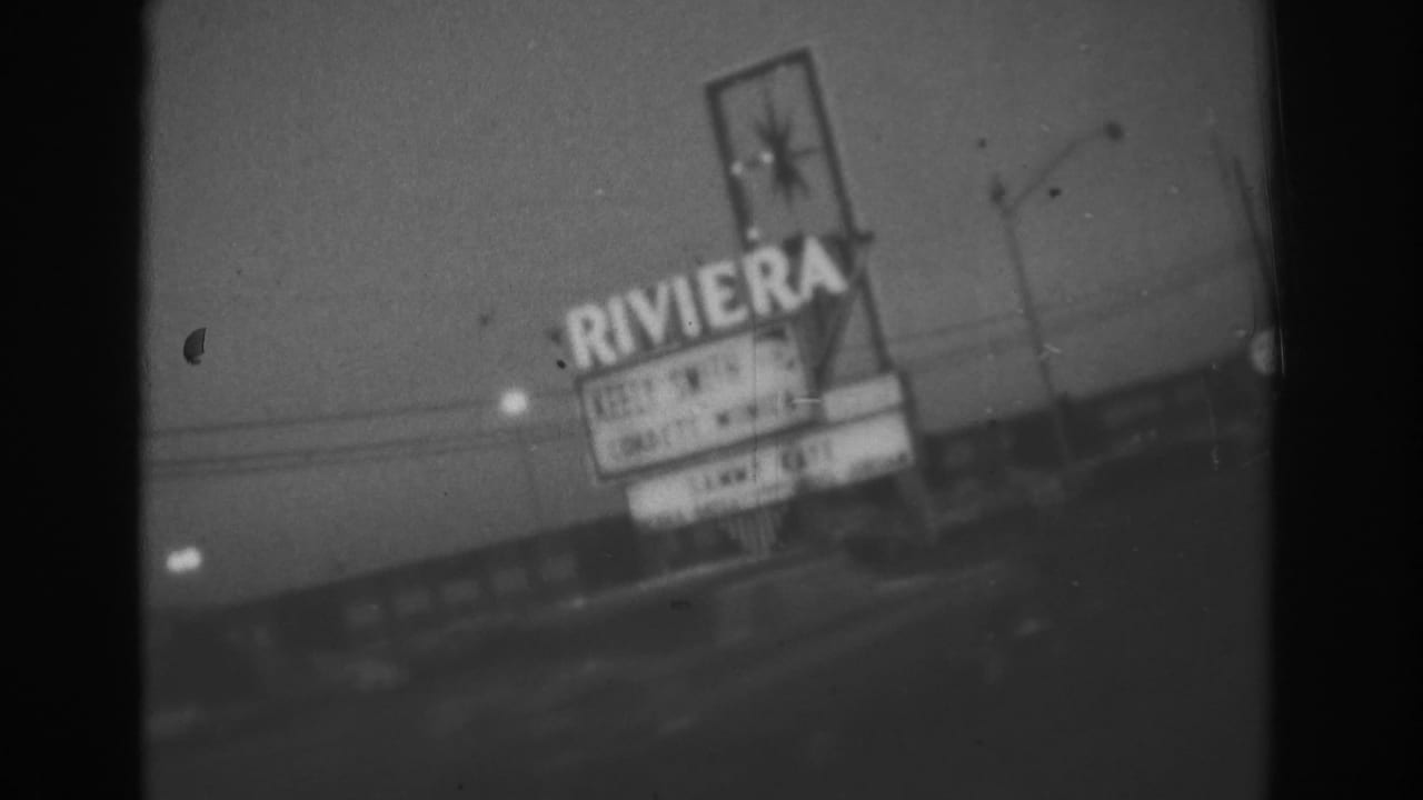 1962 Las Vegas frame showing the illuminated Riviera Hotel sign from a handheld outdoor nighttime viewpoint.