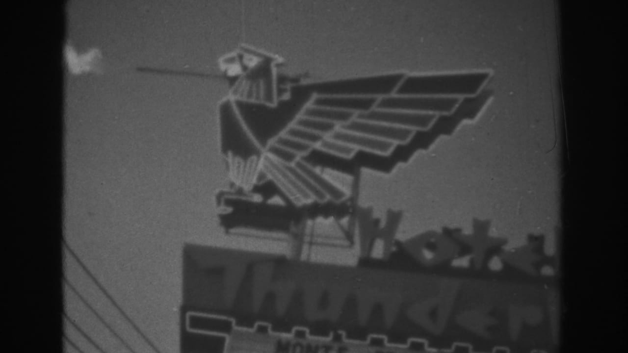 1962 Las Vegas 8mm frame showing the eagle sign, rooftop letters, overhead wires, and soft night exposure.