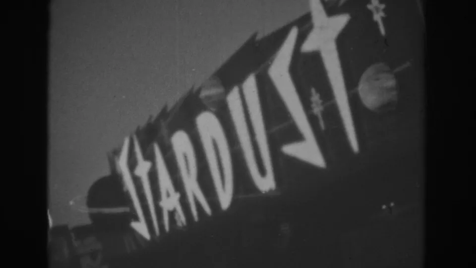 1962 Las Vegas 8mm frame showing the Stardust sign in bold lettering with star decorations against the sky.
