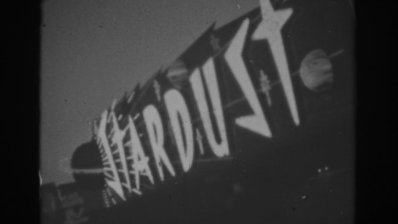 1962 Las Vegas 8mm frame showing the Stardust casino sign with bold lettering, star shapes, and a round planet-like motif against a dark sky.