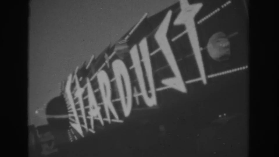 Handheld 1962 Las Vegas view of the Stardust sign, with stylized letters, star graphics, and a circular celestial motif visible at right.