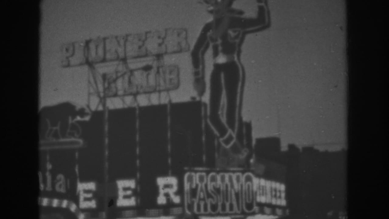 1962 Las Vegas 8mm frame showing the Pioneer Club casino sign, large cowboy figure, and clear sky in black and white.
