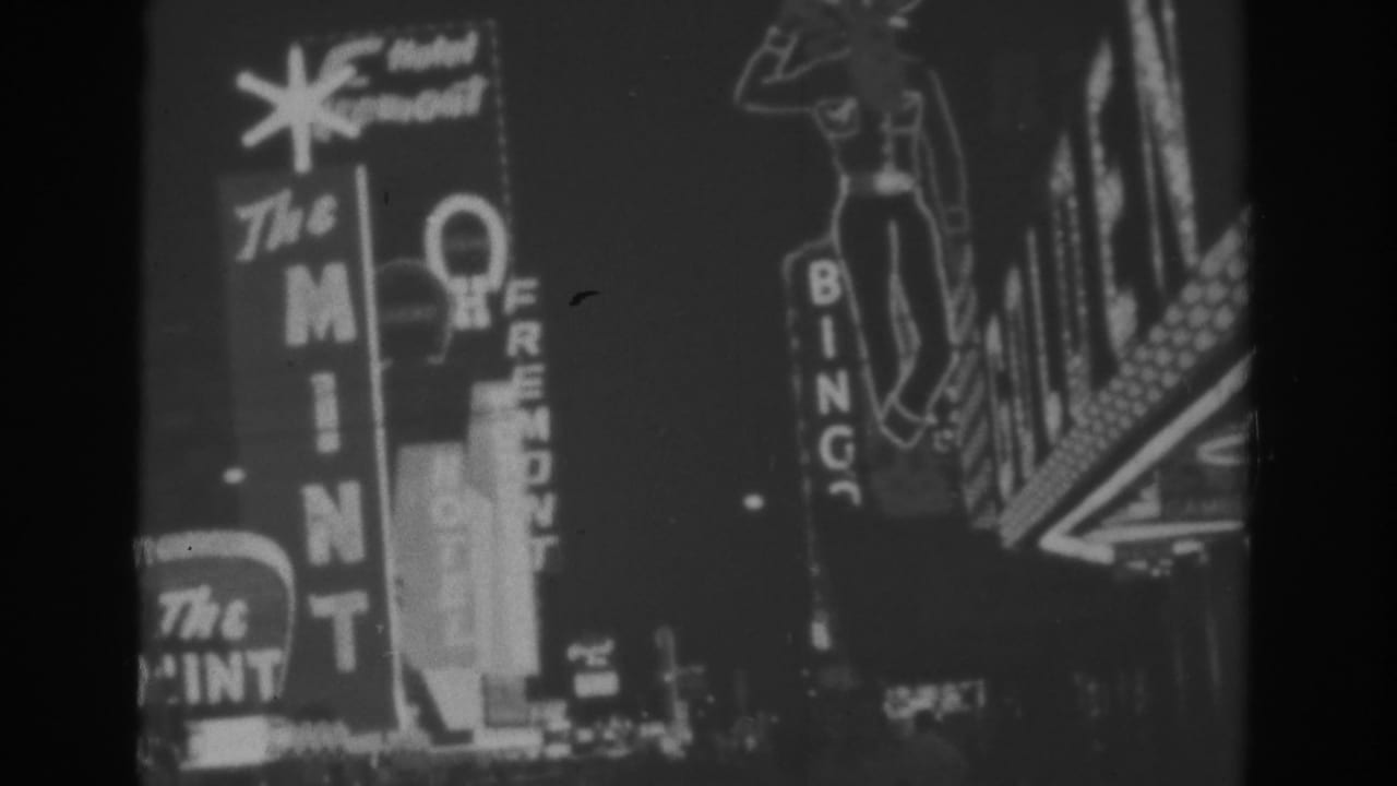 Black-and-white 8mm frame from 1962 Las Vegas showing The Mint, Hotel Fremont, and surrounding neon signage.