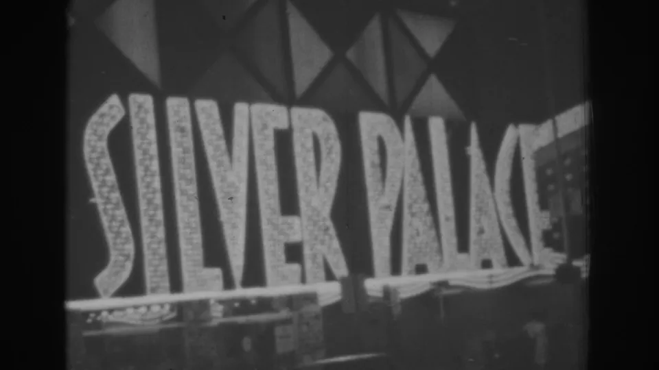 Illuminated SILVER PALACE lettering on a Las Vegas casino facade, filmed in black-and-white 8mm at night.