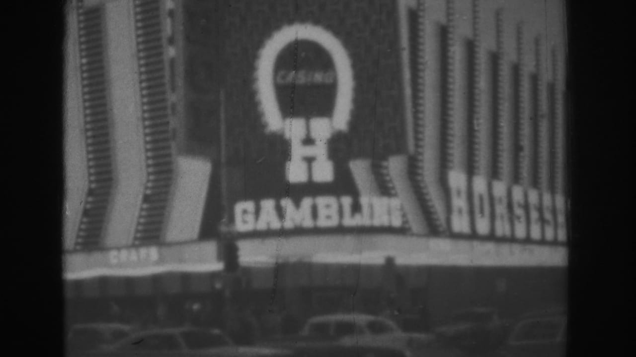 1962 Las Vegas street view showing the same casino facade with a horseshoe logo, gambling sign, vertical lights, and cars under the marquee.