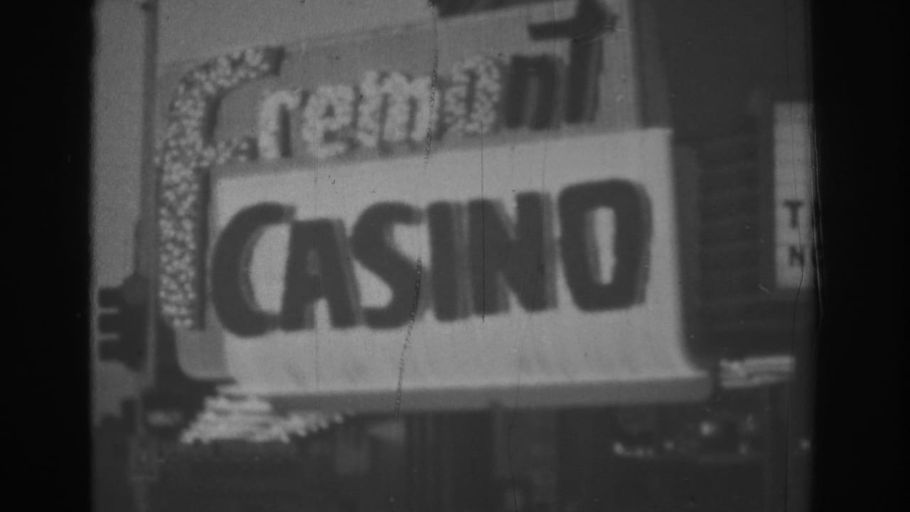 Black-and-white frame of a large Las Vegas casino sign, appearing to read Cremont or Fremont Casino, with traffic lights and street details nearby.