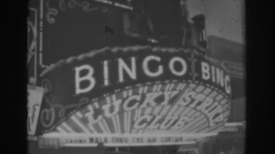 1962 Las Vegas home-movie frame with soft focus on the Lucky Strike Club marquee, BINGO lettering, and sign bulbs.