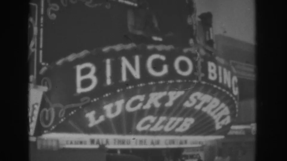 Black-and-white 8mm frame from Las Vegas showing the Lucky Strike Club marquee, BINGO sign, and surrounding neon ornament.