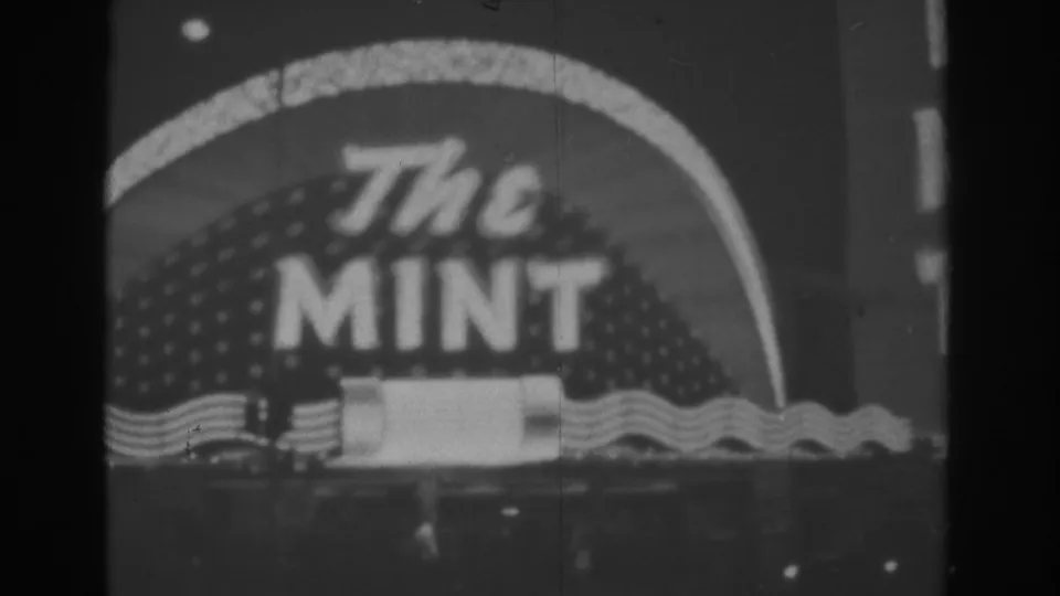 1962 Las Vegas 8mm frame showing The Mint sign with bold lettering, dotted paneling, and horizontal neon wave bands.