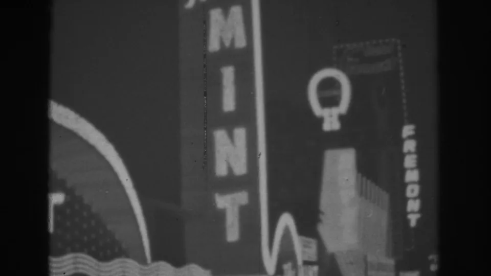 1962 Las Vegas 8mm frame showing vertical MINT lettering, part of the arched sign, and adjacent illuminated facade elements.