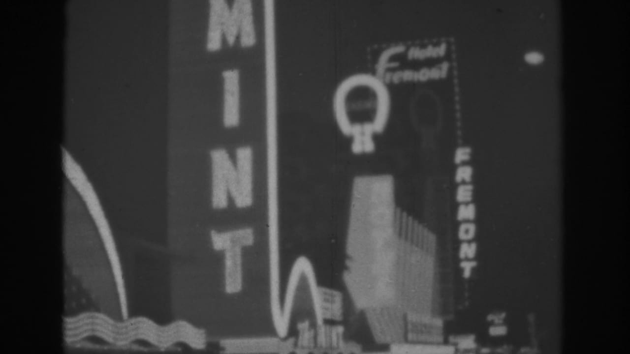 Night view of The Mint and Hotel Fremont neon signs on a Las Vegas street.