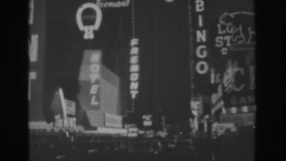 Nighttime Las Vegas frame showing Hotel Fremont, Bingo, and a bear-logo sign in soft black-and-white 8mm footage.