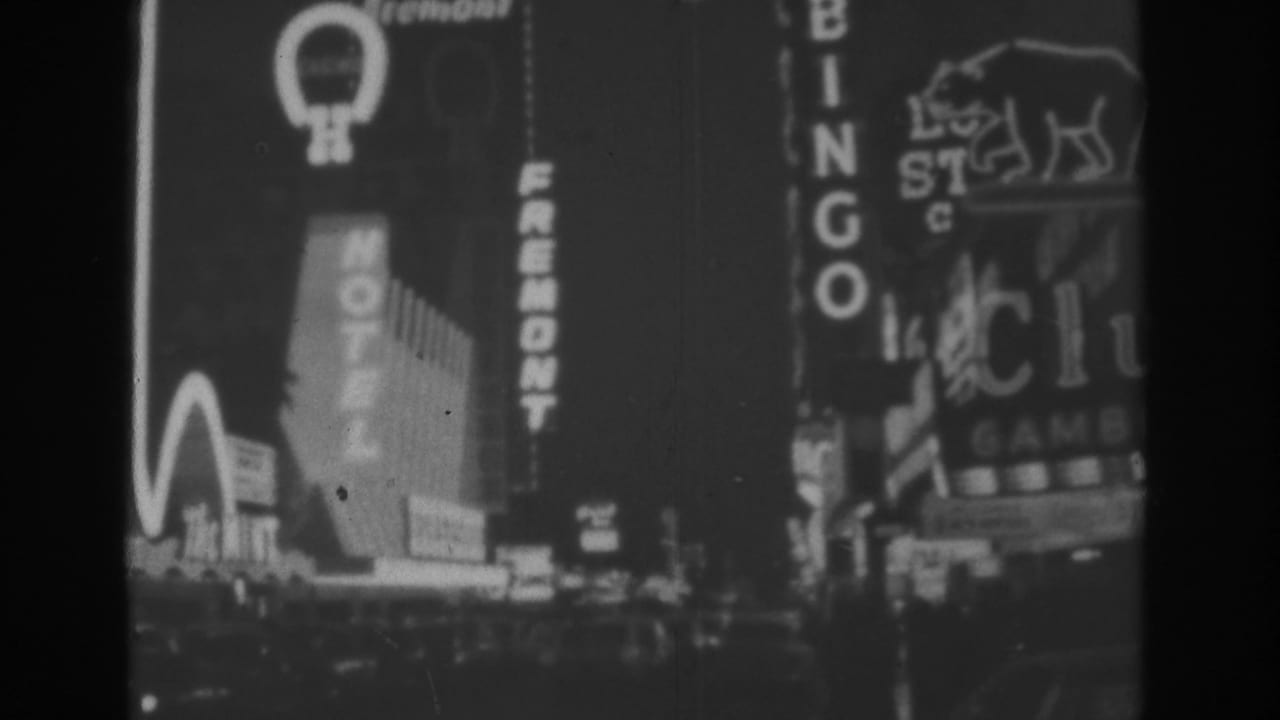 1962 Las Vegas night scene on 8mm film showing bright hotel and bingo signage along a commercial street.
