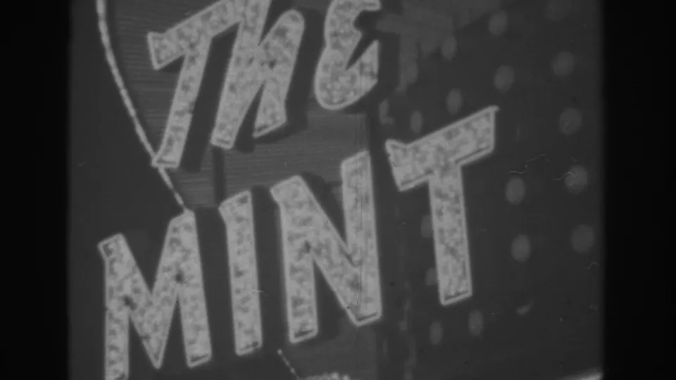 Close 1962 Las Vegas sign view showing the large illuminated lettering of The Mint in black-and-white 8mm footage.