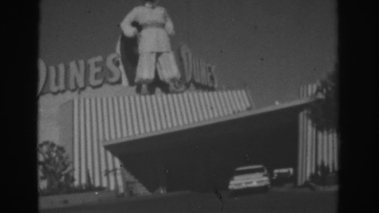 Dunes sign with rooftop statue above striped building and covered entrance.