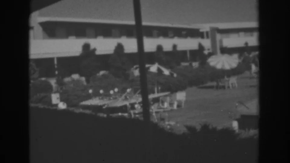 Black-and-white Las Vegas courtyard view with trees, umbrellas, seating, and a low modern building in the background.