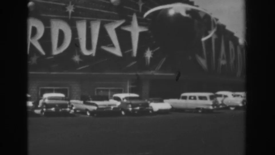 1962 Las Vegas frame with partial Stardust signage, parked cars, and a larger vehicle near the theater frontage.
